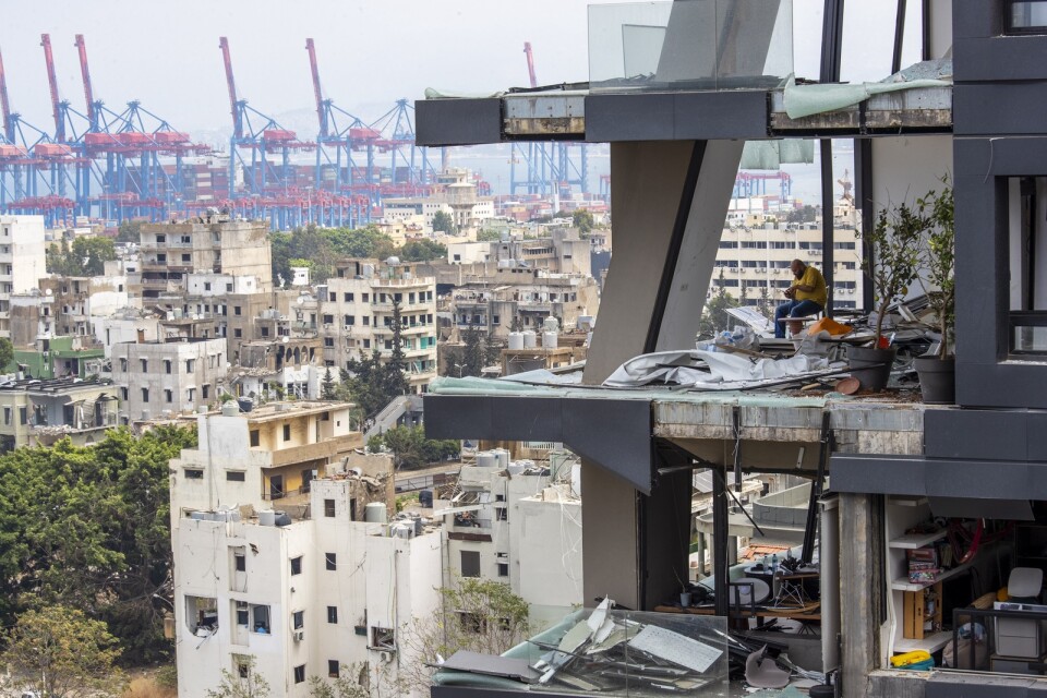 En man sitter i resterna av sin lägenhet i Beirut.