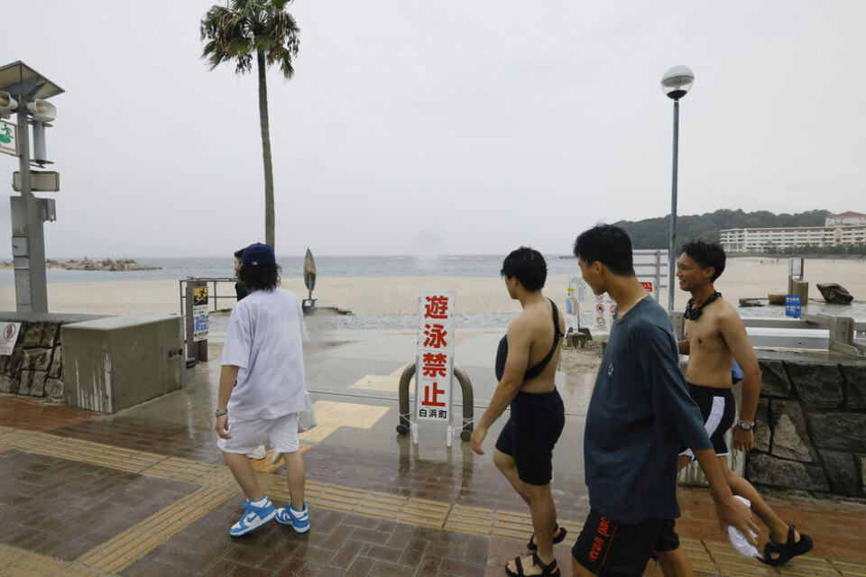 Japaner går förbi en strand som spärrats av inför tyfonens ankomst. Bilden är tagen i prefekturen Wakayama i måndags.