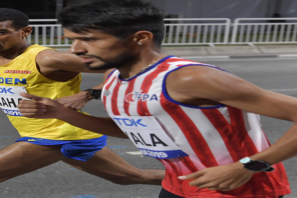 Sveriges Adhanom Abraha slänger ett öga på Paraguays Derlys Ayal i herrarnas maraton under friidrotts-VM i Doha.
