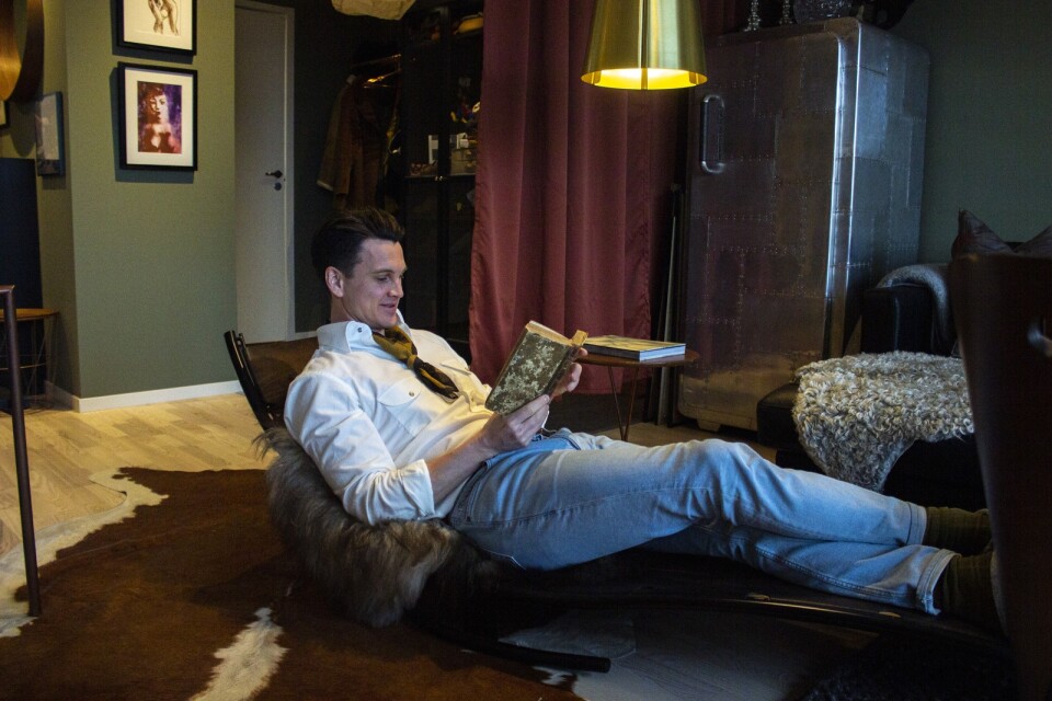 Christofer i sin favoritmöbel i lägenheten, läsandes en kokbok från 1700-talet.