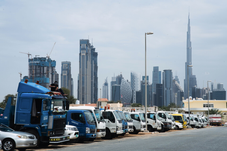 En gästarbetare arbetar på en lastbil med Dubais skyskrapor i bakgrunden. Många gästarbetare har blivit av med sina arbeten under coronakrisen och blivit strandsatta i Gulfen.