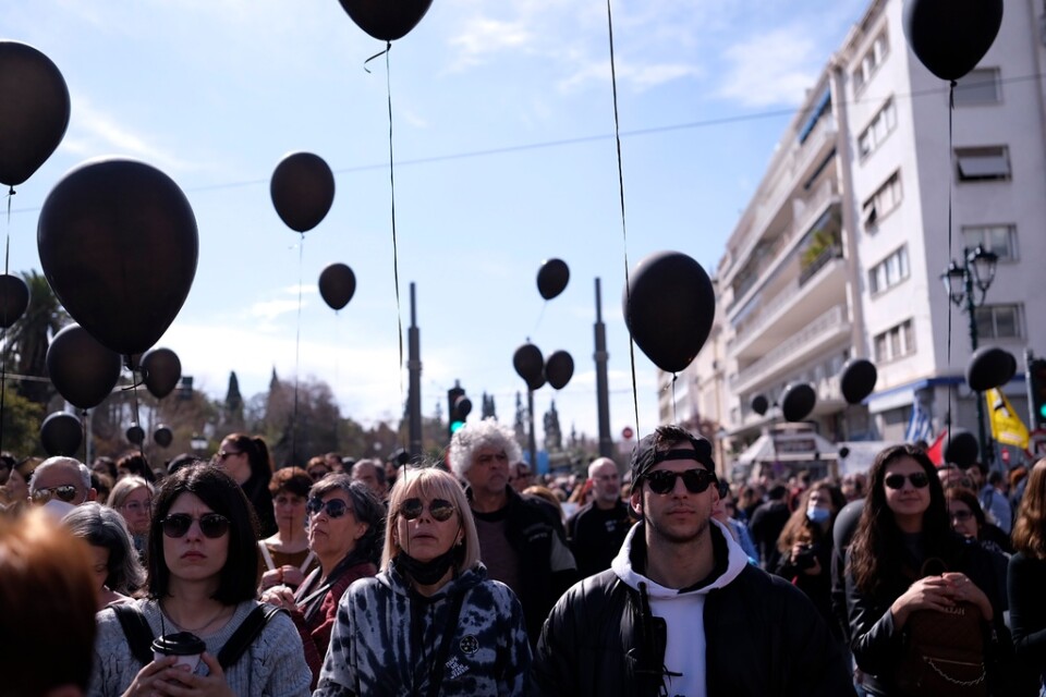 Demonstranter med svarta ballonger håller en tyst minut utanför parlamentsbyggnaden i Aten.