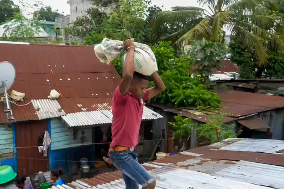 En man förstärker taket med sandsäckar i väntan på cyklonen Batsirai, som drog in över Madagaskar på lördagskvällen.