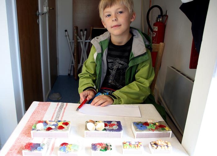 Marie Olofssons son Simon passar på att sälja tändsticksaskar med snäckor, glas och strandfynd.