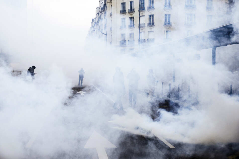 Demonstranter står i ett hav av tårgas i Paris.
