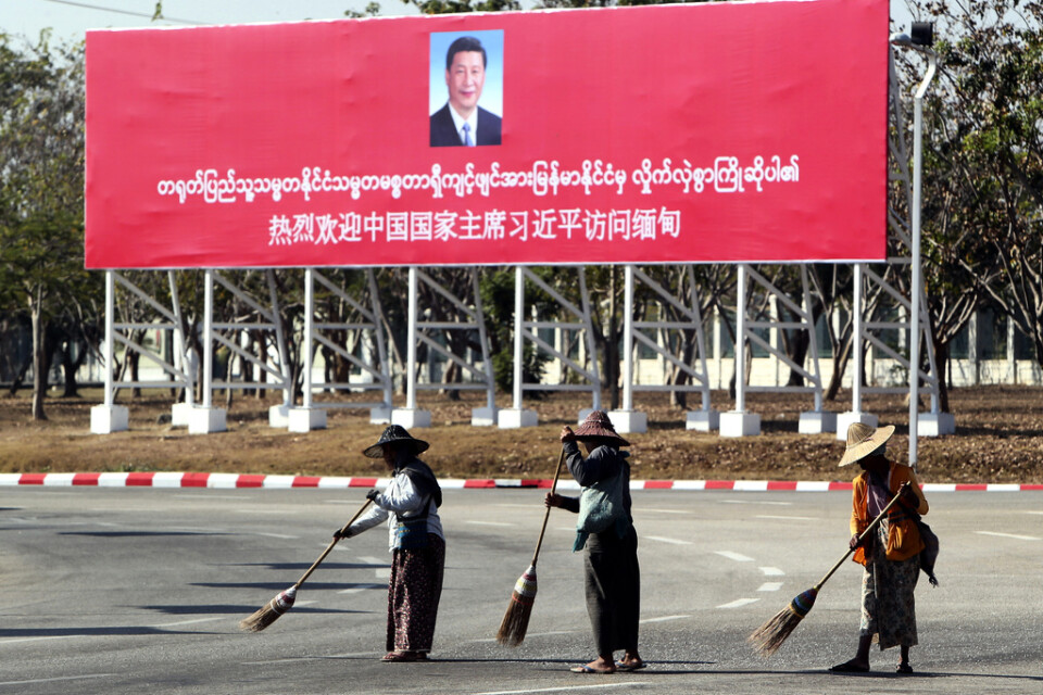 Gatan sopas framför en stor banderoll som välkomnar Xi Jinping till Myanmar.