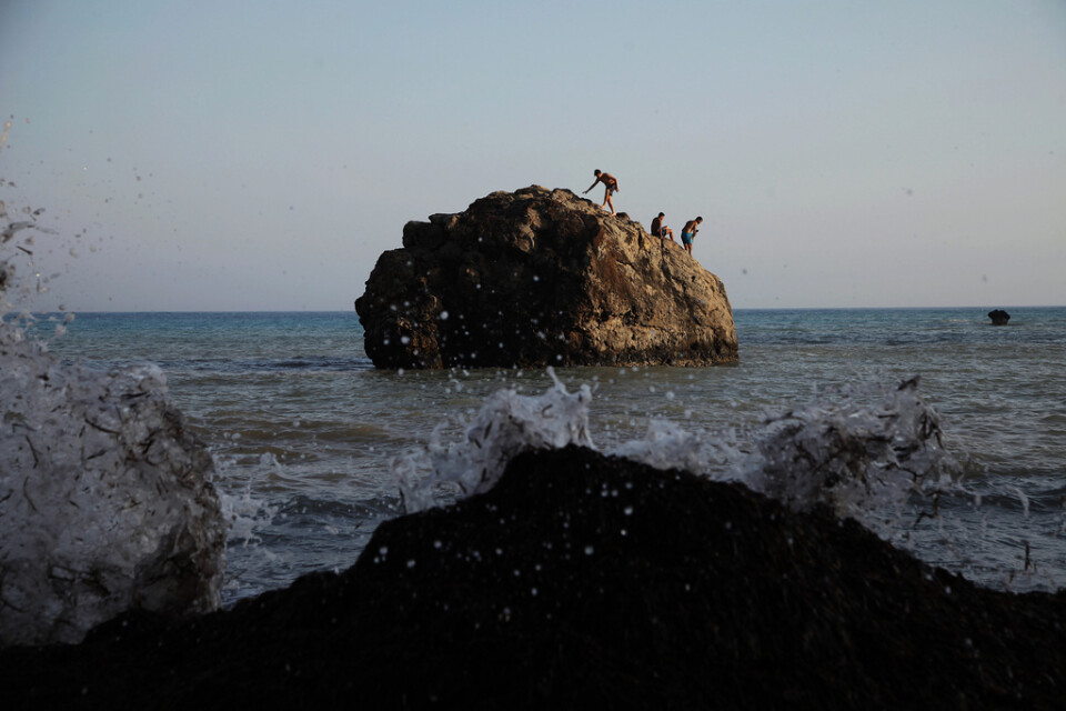Människor badar från en klippa nära staden Pafos på Cypern. Arkivbild från juli i år.