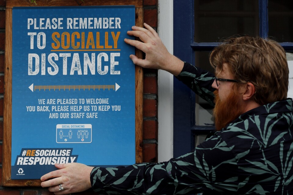 En skylt med information om social distans sätts upp på en pub i London.