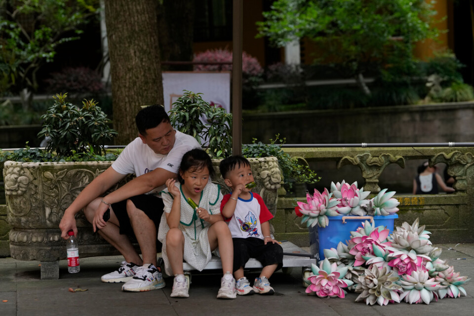 Barn svalkar sig i skuggan i Hangzhou i östra Kina.