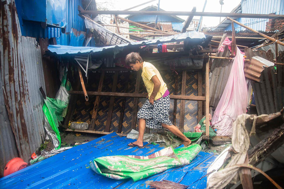 En kvinna går förbi skadade byggnader i delstataten Rakhines huvudstad Sittwe.