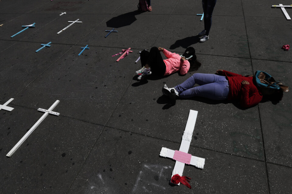 Kvinnor ligger sida vid sida med kors till minne av mordoffer under en demonstration i Mexico City i mars.