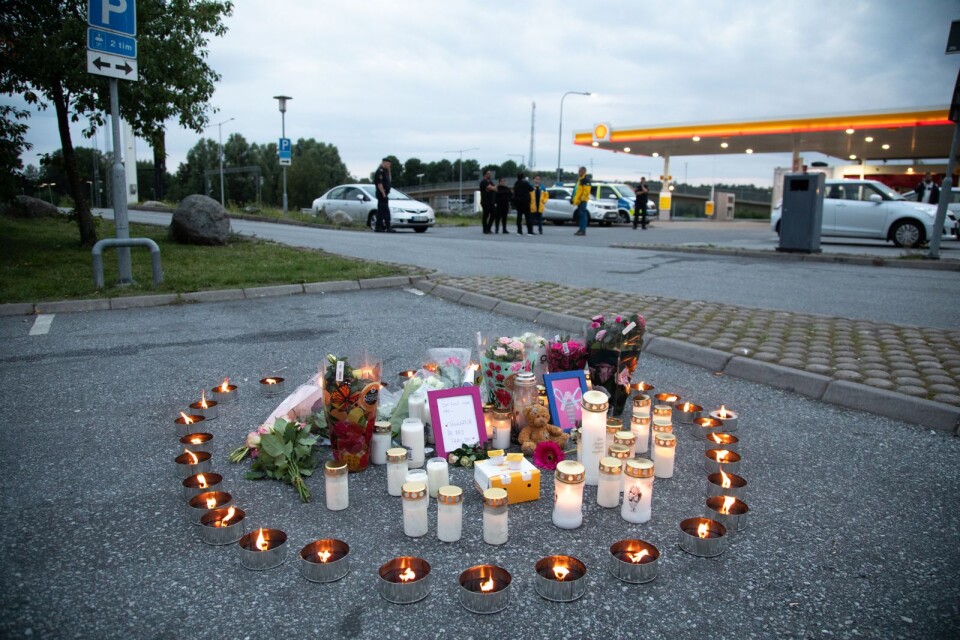 Blommor och ljus på platsen där en tolvårig flicka skottskadades söder om Stockholm natten mot söndagen. Flickan avled senare på sjukhus