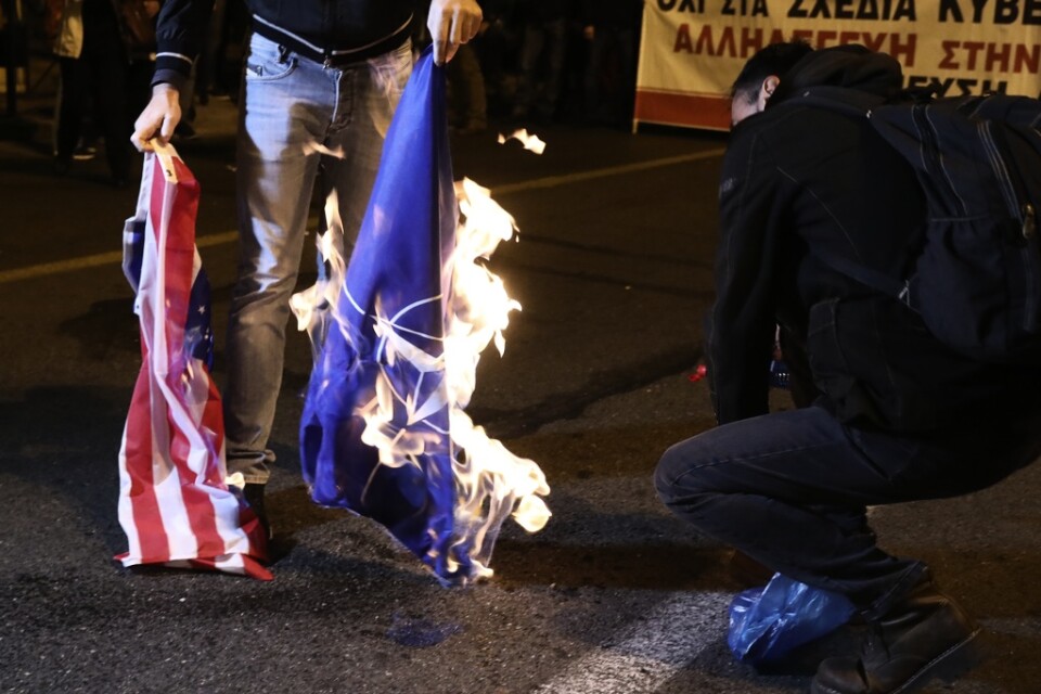 En demonstrant i Aten bränner USA:s och Natos flaggor under en minnesmarsch för att hedra offren i en studentprotest mot militärjuntan 1973.