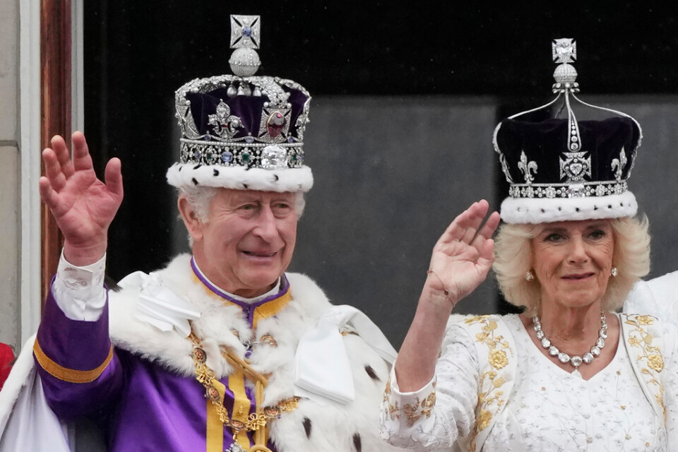 Storbritanniens nykrönte kung Charles och drottning Camilla vinkar till folkhavet framför Buckingham Palace efter att kröningsceremonierna är avklarade.