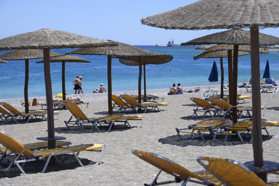 Turister njuter av solen på en strand på den grekiska ön Rhodos. Arkivbild.