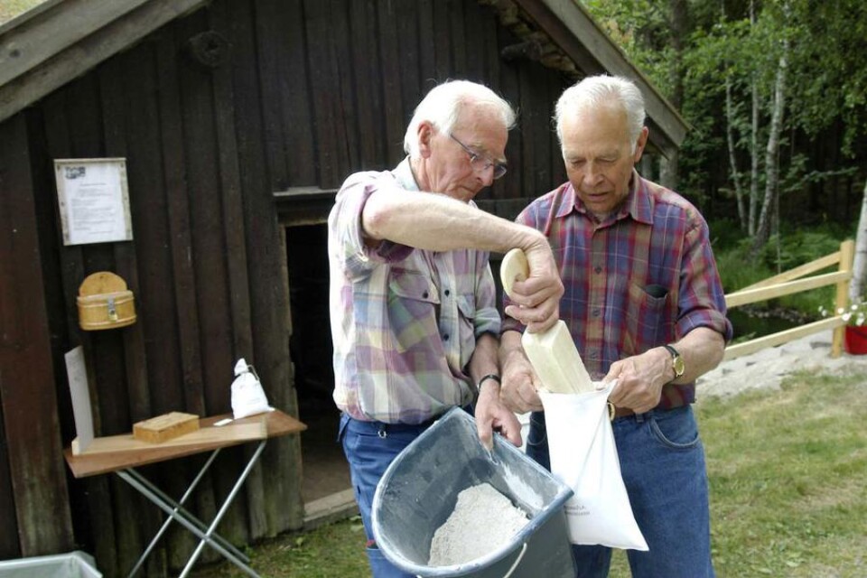 Sten-Inge Gustafsson och Stig Andersson fyller påsar med nymalet mjöl från skvaltkvarnen i Siggamåla.